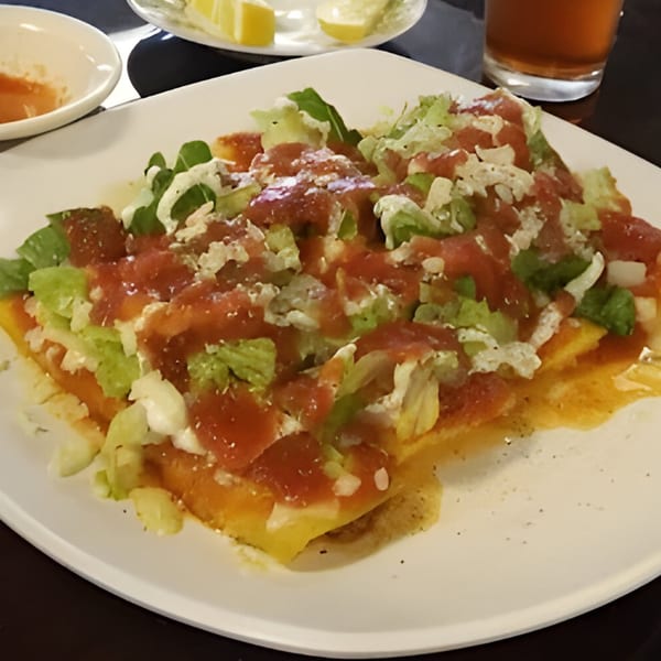 Mi Rinconcito's Mexican dish with red sauce, lettuce, and white cheese on a white plate.
