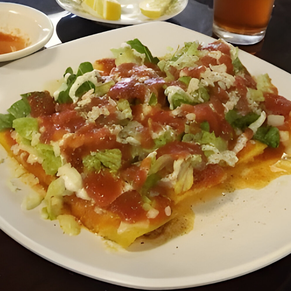 Mi Rinconcito's Mexican dish with red sauce, lettuce, and white cheese on a white plate.