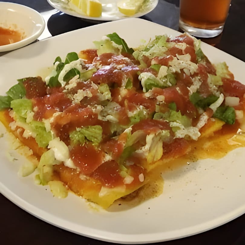 Mi Rinconcito's Mexican dish with red sauce, lettuce, and white cheese on a white plate.